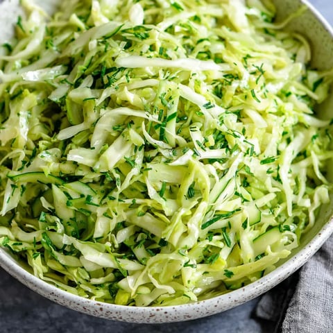 A bowl of green cabbage and cucumber salad.