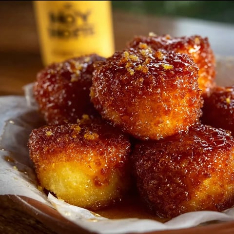 A plate of doughnuts with a bottle of hot honey ranch sauce.