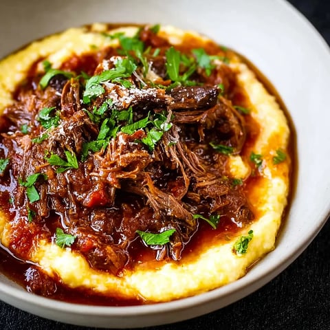 A bowl of short ribs in a red sauce.